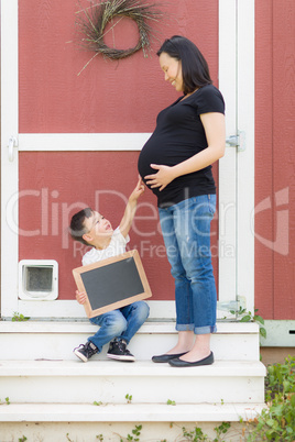 Son with Blank Chalk Board Pointing to Pregnant Belly of Mommy