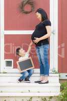 Son with Blank Chalk Board Pointing to Pregnant Belly of Mommy