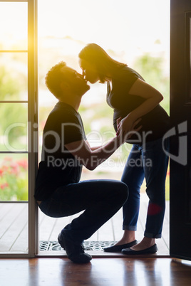 Mixed Race Pregnant Couple Kissing Silhouetted in Doorway.