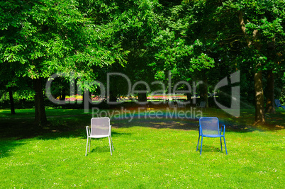 Summer park, green lawn, garden chairs and an automatic watering