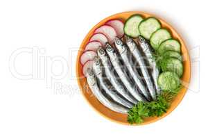 Small salted fish anchovies on the plate with cucumber and herbs
