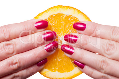 Hand with manicured nails touch an orange on white