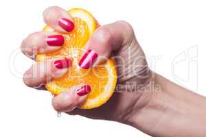 Hand with manicured nails touch an orange on white