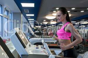 Shot of focused girl running on treadmill in gym