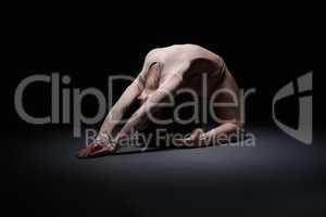 Flexible female gymnast exercising in dark studio