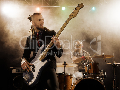 Rock band performs on stage. Bassist in the foreground.