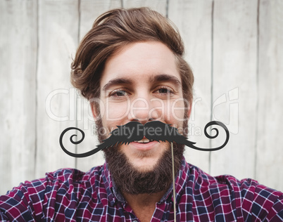Composite image of happy hipster against wooden fence