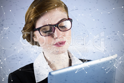 Composite image of redhead businesswoman using her tablet pc