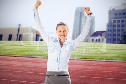Composite image of successful businesswoman raising arms