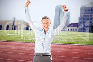 Composite image of successful businesswoman raising arms