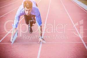 Composite image of businessman in the starting blocks holding a