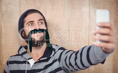 Composite image of hipster making face while taking selfie on mo