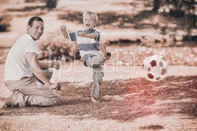 Father playing football with his son during the summer