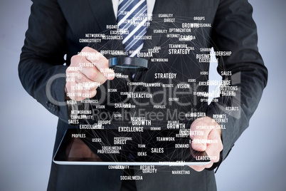 Composite image of businessman looking at tablet with magnifying