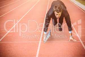 Composite image of businessman in the starting blocks holding la