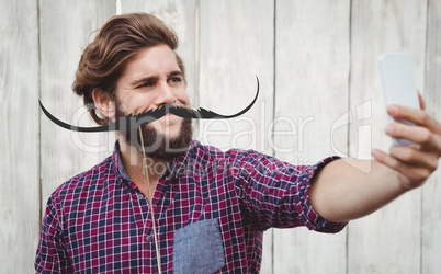 Composite image of hipster taking selfie against wooden wall