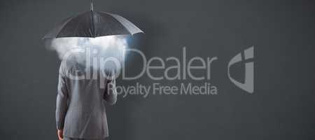 Composite image of businessman standing under umbrella