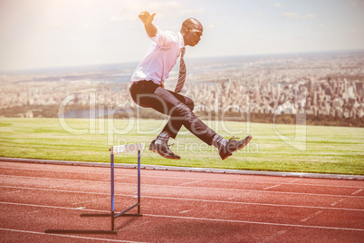 Composite image of businessman jumping a hurdle