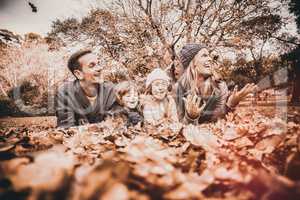 Smiling young family throwing leaves around