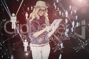Composite image of smiling trendy blonde using tablet computer