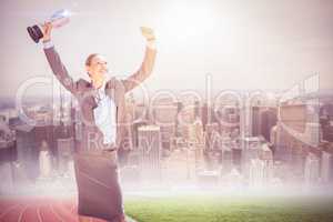 Composite image of successful businesswoman lifting a trophy