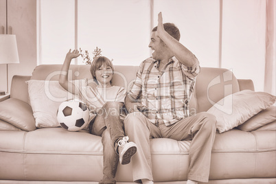 Father and son giving high-five while watching soccer match