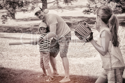 Family playing baseball in the park