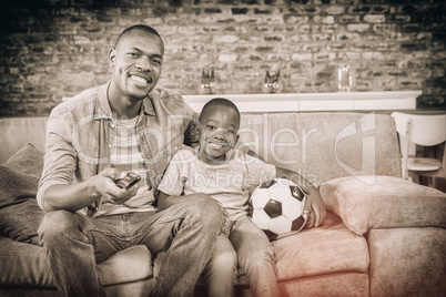 Father and son watching tv together on the couch