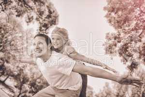 Father giving daughter a piggy back in park