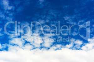 Horizontal bottom aligned white cloudscape on blue sky backgroun
