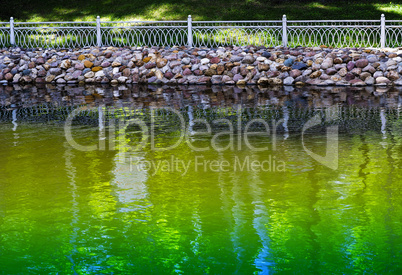 Horizontal vivid park fence near green pond background