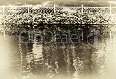 Horizontal sepia vignette park fence near lake background