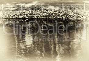 Horizontal sepia vignette park fence near lake background