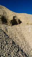 Vertical vivid heap of rock with vibrant blue sky background