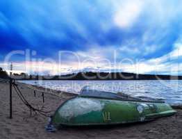 Flipped over boat on sand dramatic beach background