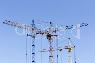 Industrial landscape with silhouettes of cranes on the sky backg