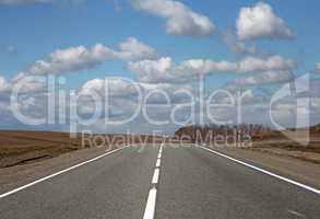 Asphalt road and clouds on blue sky in sunny day