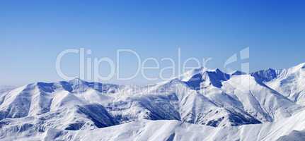 Panoramic view on snowy winter mountains and blue sky