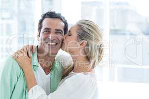 Mid adult woman kissing man at home