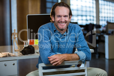 Creative businessman sitting on chair against computer desk