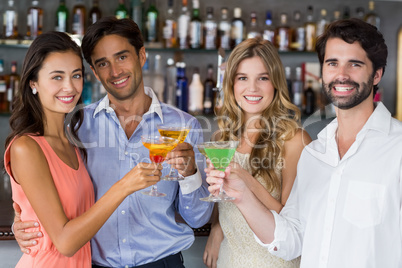 Portrait of happy couples toasting cocktail glasses