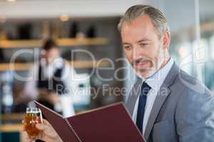 Businessman holding glass of beer and looking at menu