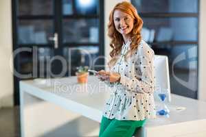 Portrait of smiling woman using mobile phone in office