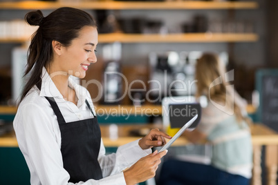 Smiling waitress using digital tablet