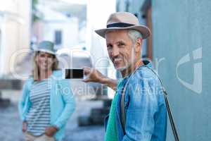 Man photographing woman in city