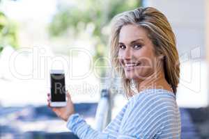 Cheerful woman holding smartphone at street