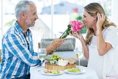 Man giving pink roses to wife in restaurant