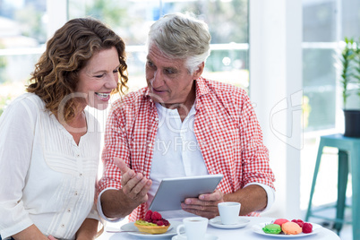 Man explaining woman over digital tablet