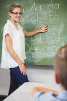 Smiling teacher teaching kids on chalkboard in classroom