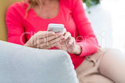 Woman using mobile phone on couch at home